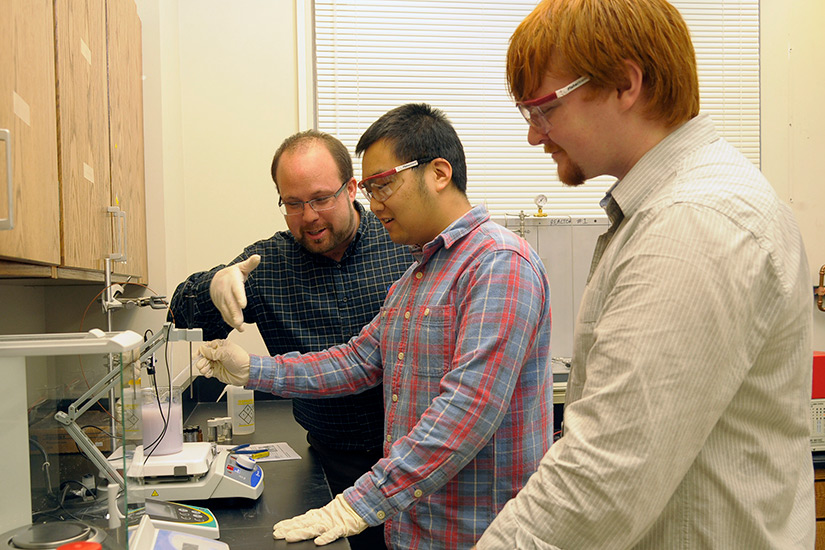 Siris Laursen instructs two students in a laboratory.