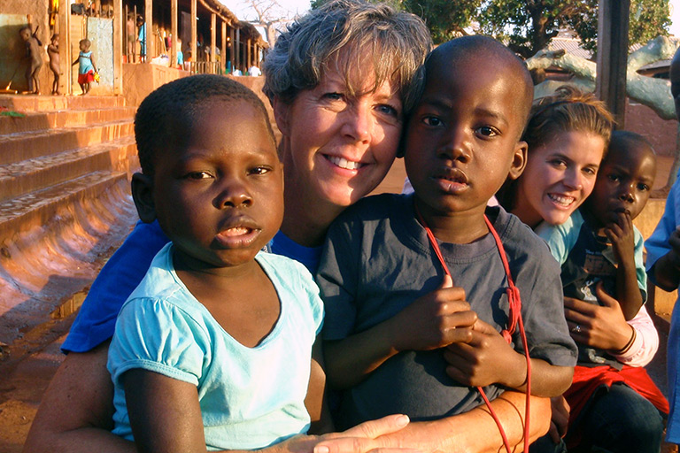 Angie poses with children while on a mission trip.