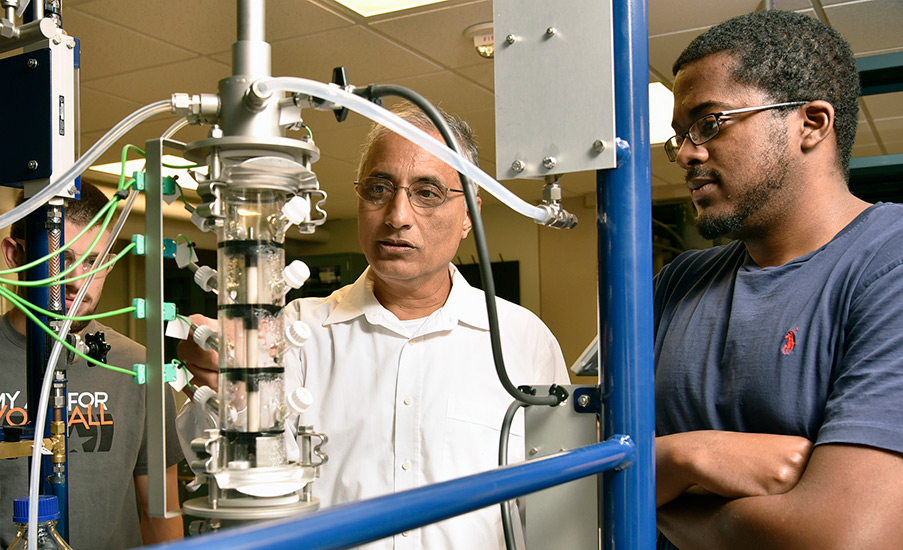 Sankar Raghavan instructs student in a laboratory.