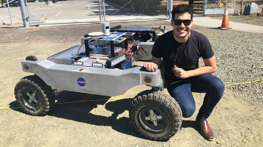 Erick Ribiero poses with a NASA vehicle.