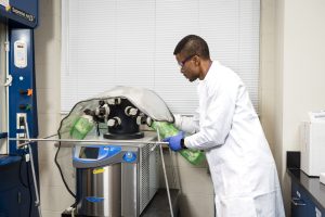 Christian Kemefa setting up a machine in a lab to run experiments