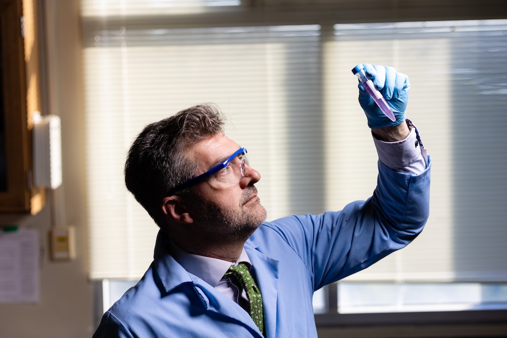 Paul Dalhaimer looking at something in a tube in a lab