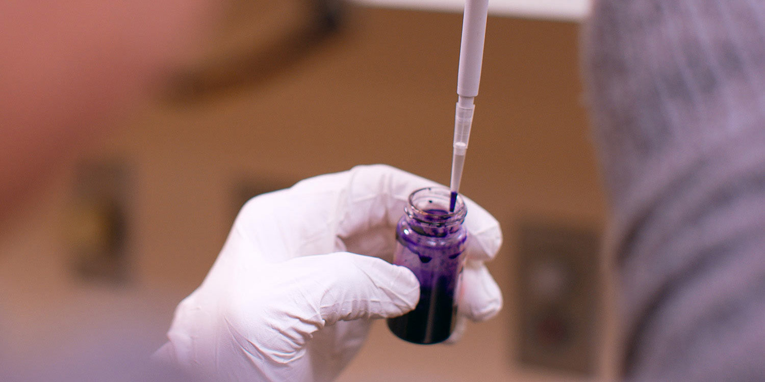 Close up of student's hand extracting a liquid using a dropper.