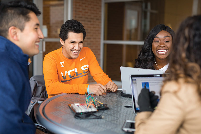 Four students sit at a table at UT.
